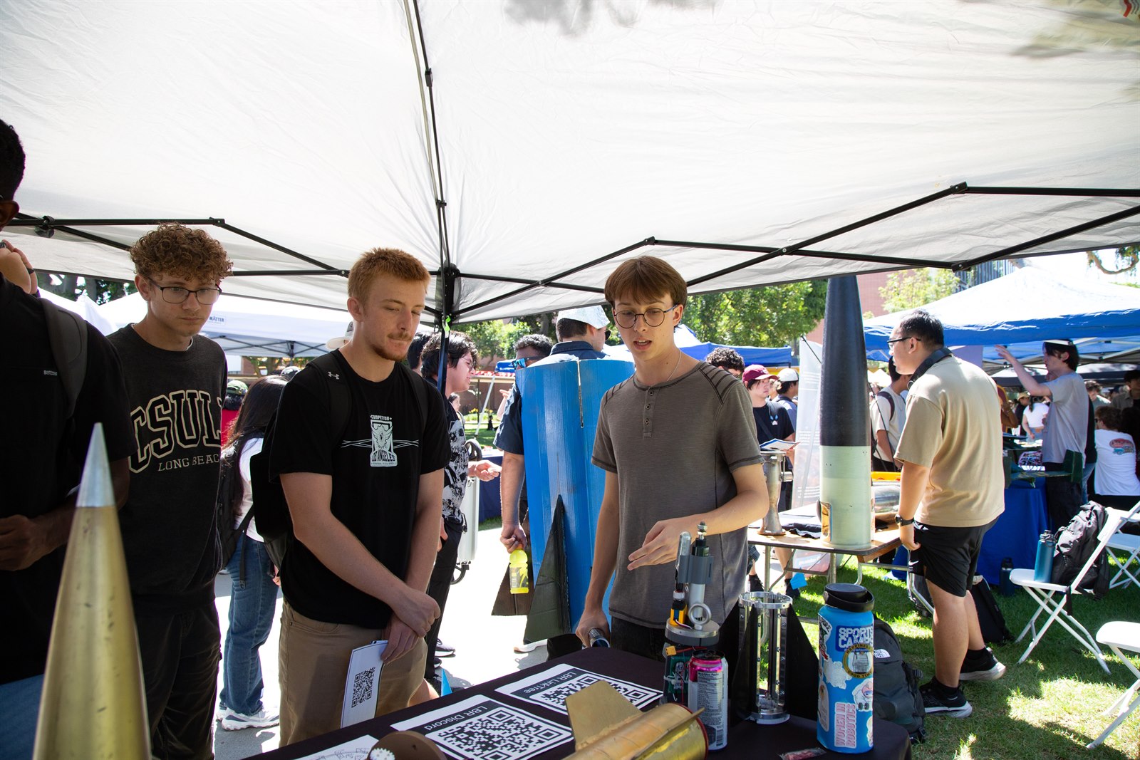 Long Beach Rocketry members demonstrating a rocket and hardware display to students at WOW Fall 2025