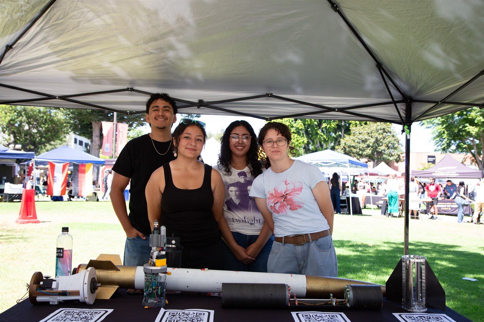 Four Long Beach Rocketry members posing behind a rocket display at WOW Fall 2025